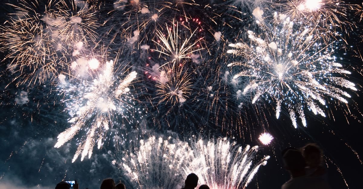 Backyard fireworks show with colorful bursts over a family celebration