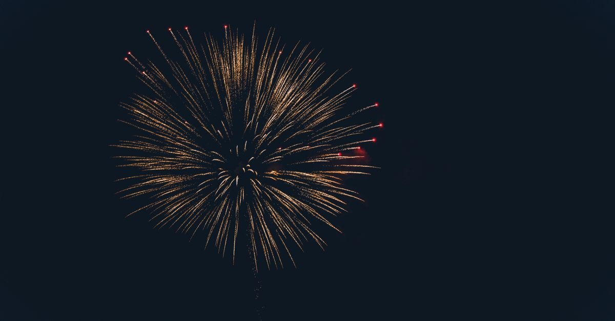 Golden firework burst illuminating the night sky, illustrating the boom and sound of fireworks